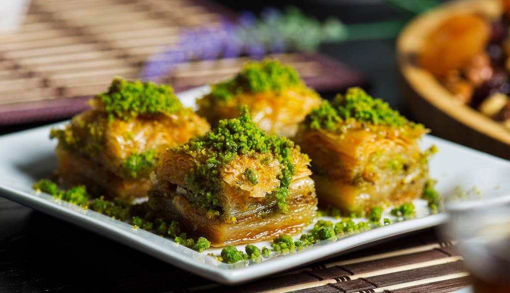 Enjoy a mouthwatering close-up of authentic baklava topped with vibrant pistachios. Perfect for food lovers.